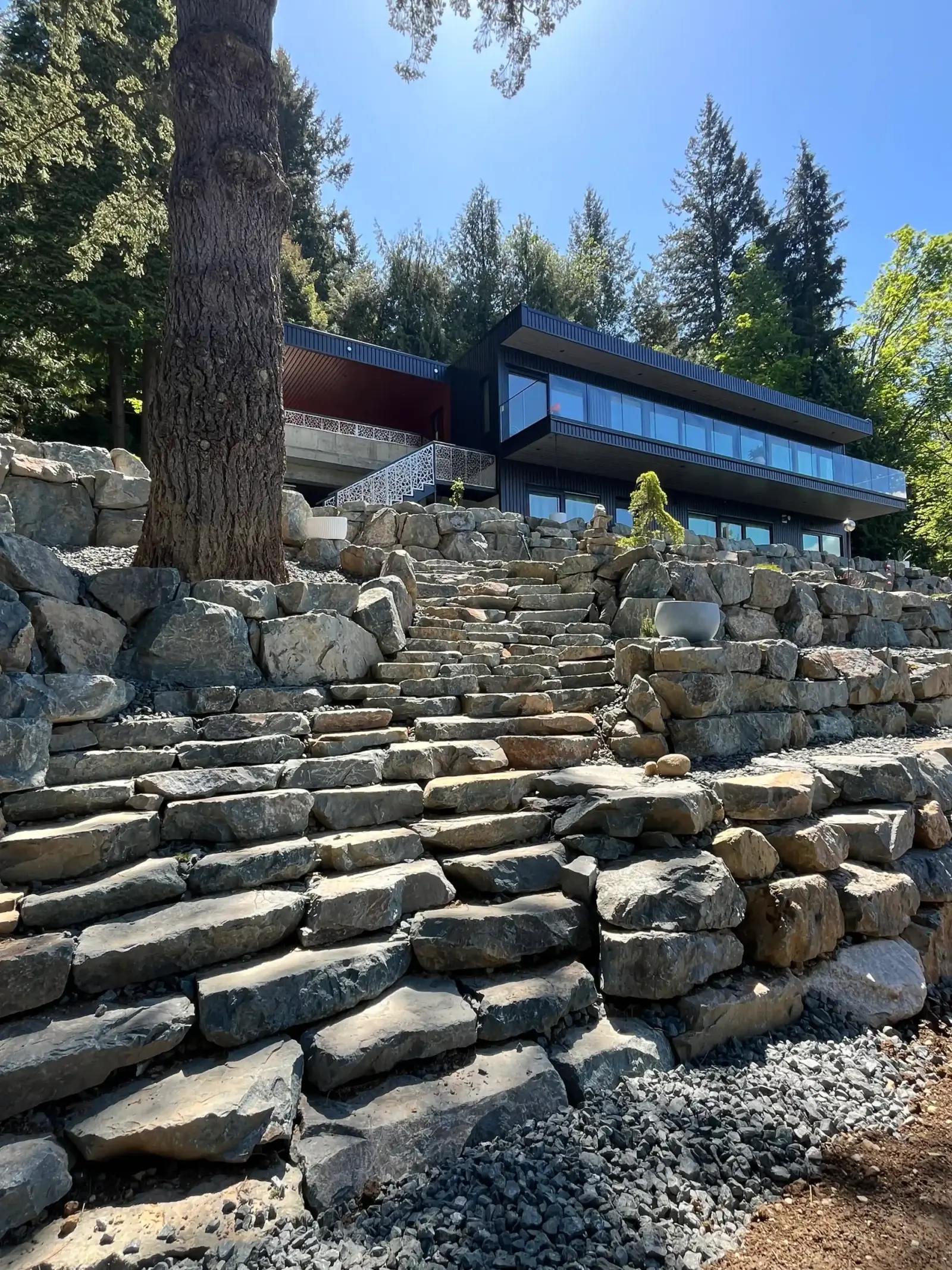 Terraced rock retaining walls and stone steps leading up to a modern Chilliwack home