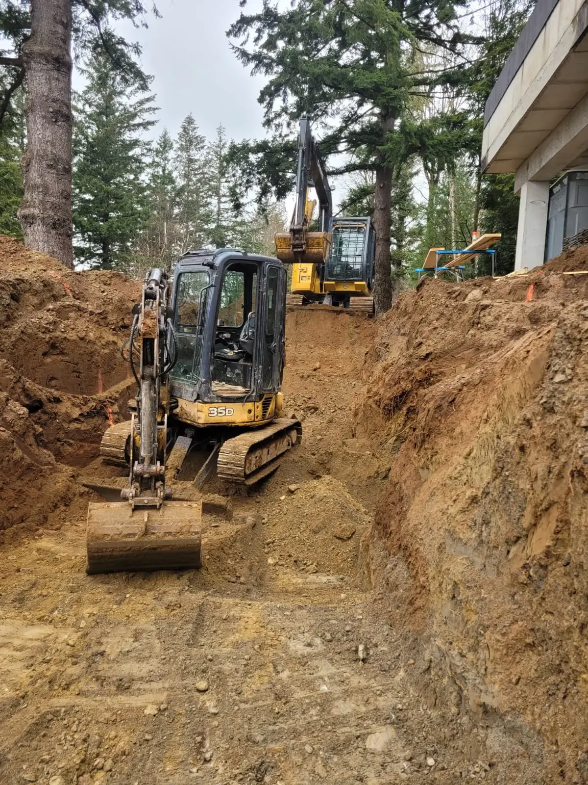 A mini excavator digging beside trees