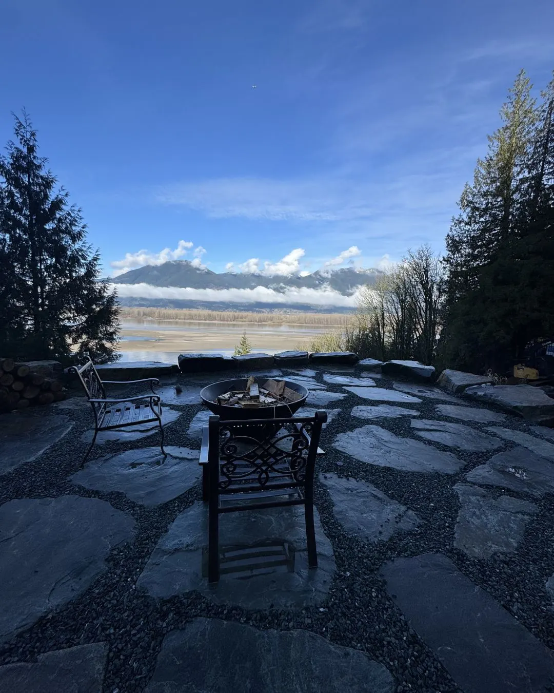 A stone patio and fire pit with mountains behind