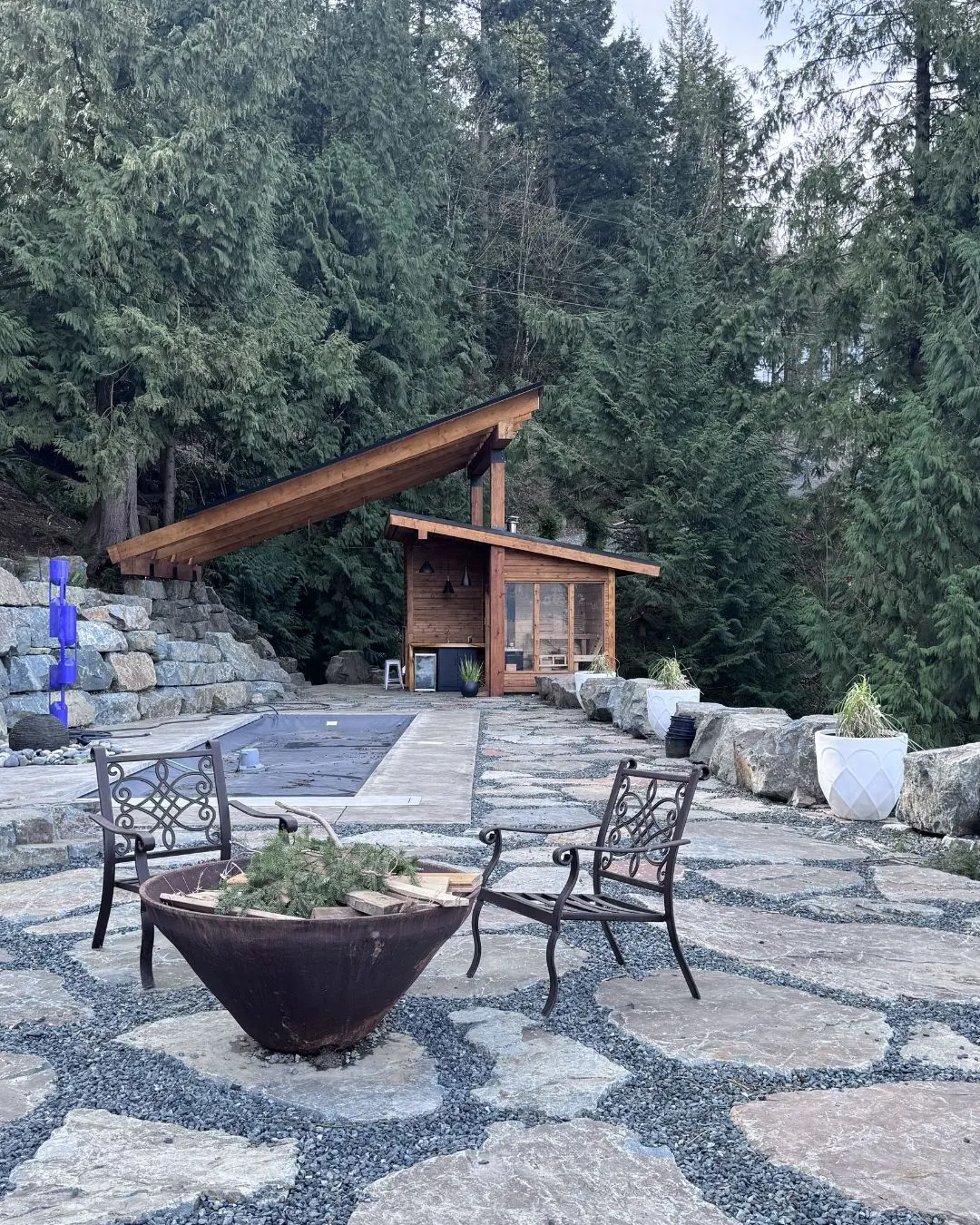 A cedar pavilion and fire bowl on a stone patio